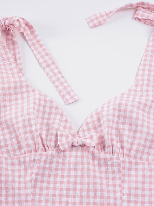 Close-up of a pink gingham dress with bow straps on a white background