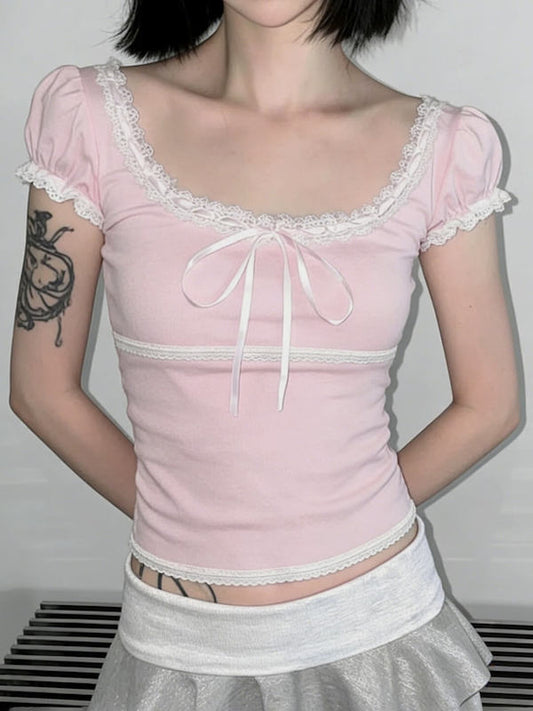 Person wearing a pink lace top with puffed sleeves against a plain background